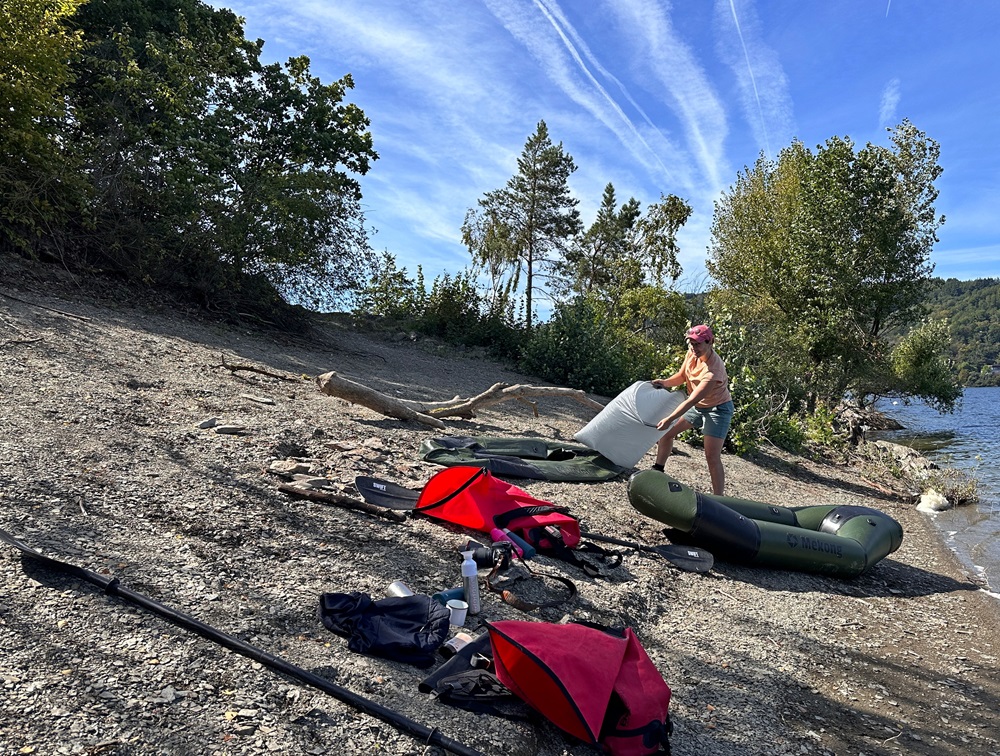 Uppblåsning av en packraft på sjöstranden under ett packraftingäventyr i Eifel, Tyskland